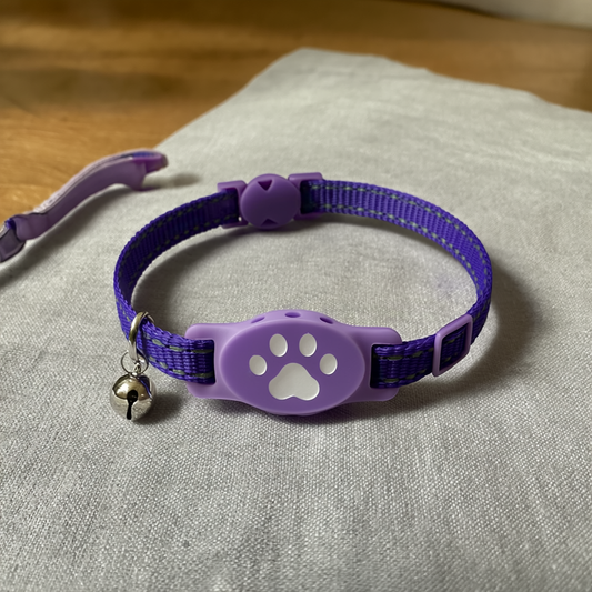 Purple breakaway cat calming collar with paw-print pheromone holder and bell on soft linen